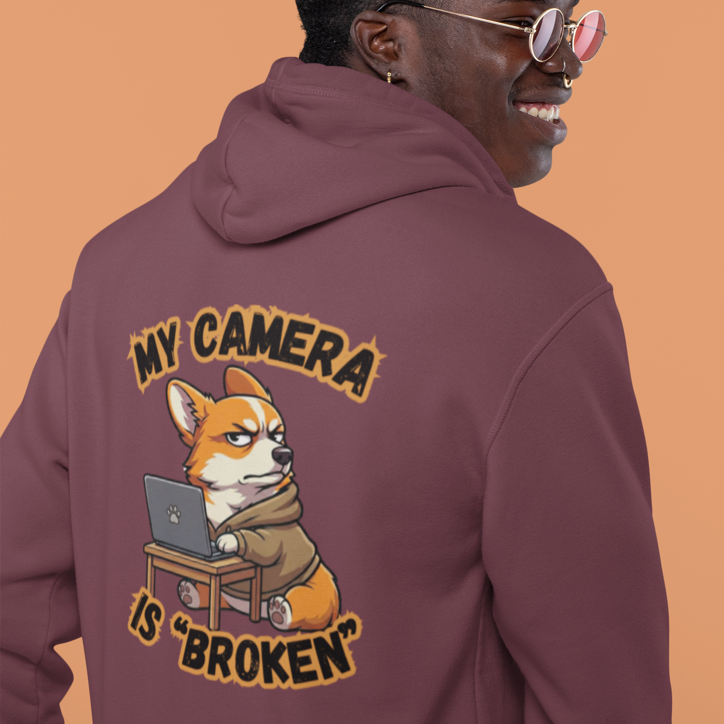 Person wearing a maroon hoodie with a graphic design on the back against an orange background